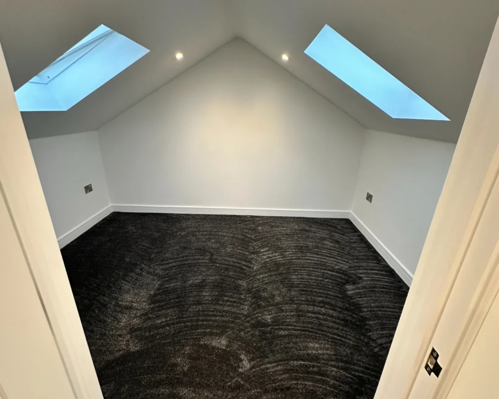 photo of a Loft Conversions in Bridgend & South Wales newly renovated loft with skylights and dark carpet flooring, ready for finishing touches