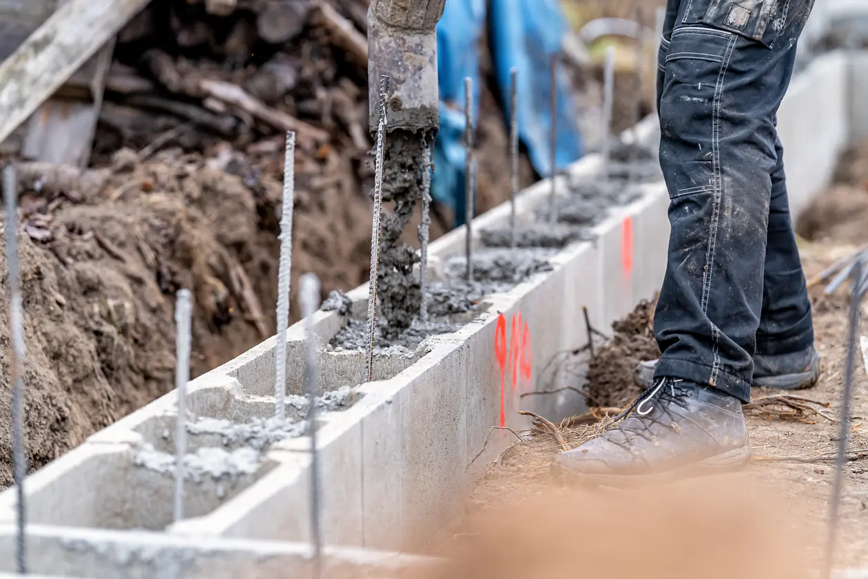 Builders laying concrete blocks for extension foundation work in Wales